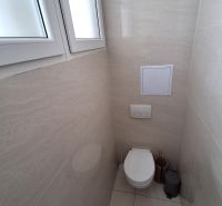 A bathroom in the office with a closed toilet and simple tiles.