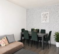 Dining area with a dark table and chairs in a three-room apartment with a wooden decor floor.