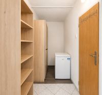 A hallway with a white floor, a shelving cabinet, and a small refrigerator, a 3-room apartment.