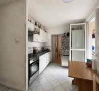 A kitchen in a 3-room apartment with a kitchen unit, stove, and table on tiles.