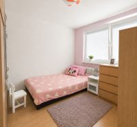 A room in a 3-room apartment with pink bed linens, a wardrobe, and a wooden decor floor.