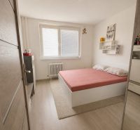 A bedroom in a 3-room apartment with a wooden decor floor and a simple bed.
