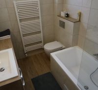 A bathroom in a 2-room apartment with a bathtub, a sink, and a floor with a wooden decor.