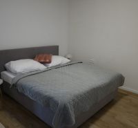A bedroom in a two-room apartment with a wooden decor floor and a bed.