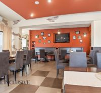 Restaurant interior with an orange wall, seating, and decorations in dining spaces.