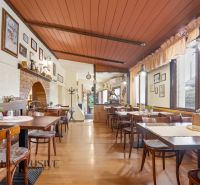 Gastro premises with wooden decor flooring, tables, and wall decorations.