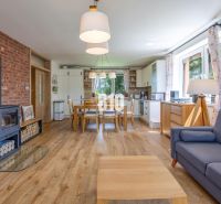 Living room with wood-patterned flooring, a fireplace, and a dining table in a family house.