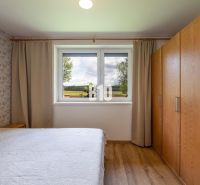 Bedroom with wood-patterned flooring and a view from the window in a family house.