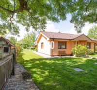 A family house in Bílkove Humence surrounded by a garden with trees and a lawn.