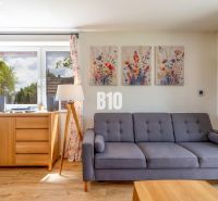 Living room with a sofa, paintings, and a wooden-patterned floor in a family house.