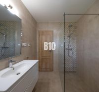 Modern bathroom with a large mirror, shower stall, and minimalist furnishings.