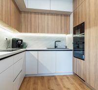 A kitchen in a 3-room apartment with a wooden decor floor and built-in appliances.
