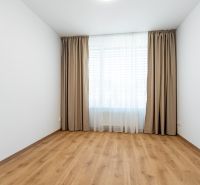 A room in a 3-room apartment with a wooden decor floor and curtains on the window.