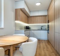 A kitchen with a table in a 3-room apartment, a floor with a wooden decor, and built-in appliances.