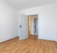 White room with wood-patterned flooring and doors in a 3-room apartment.