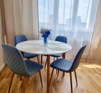 Dining area with a round table, blue chairs, and a wood-patterned floor.