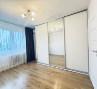 A bright room in a 3-room apartment with a wooden decor floor and a built-in wardrobe.