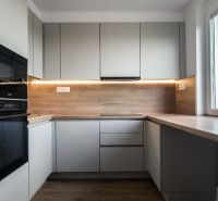 A kitchen with built-in appliances, light cabinets, and a wood-patterned floor in a three-room apartment.