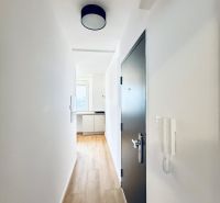 A corridor with a light interior, white walls, and a floor with a wood decor.