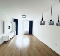 Living room in a three-room apartment with a wooden decor floor and hanging lamps.