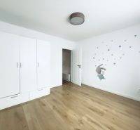 Children's room in a three-room apartment with a wood-patterned floor and white furniture.