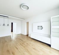 Living room of a three-room apartment with white furniture and a wooden decor floor.