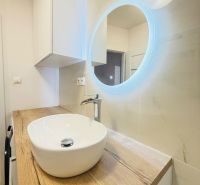 A bathroom in a 3-room apartment with a designer sink and illuminated mirror.