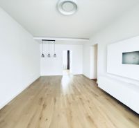 Living room in a three-room apartment with white walls and a floor with a wooden decor.