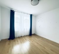 A bright room with a wooden decor floor and dark curtains in a 3-room apartment.