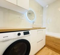 Bathroom in a 3-room apartment with a washing machine, sink, and bathtub, floor with wooden decor.