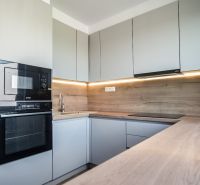 A kitchen in a 3-room apartment with a wood-patterned floor and built-in appliances.