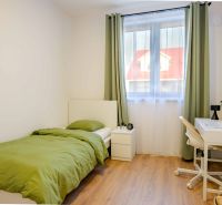 A simple room with green bedding and a wood-patterned floor.