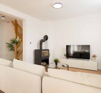 Living room in a family house with a television, fireplace, and wooden decor flooring.