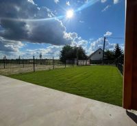 A garden with a lawn and paving at a family house in Andovce on a sunny day.