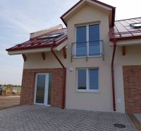 A family house in Andovce with a brick cladding and a red roof, excavator in the background.