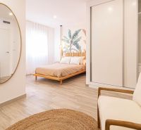 Interior of a holiday apartment with a bed, mirror, and wooden decor flooring.