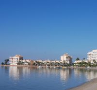 The coast with holiday apartments in La Manga del Mar Menor by the calm sea and blue sky.