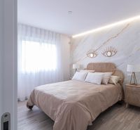A bedroom in a holiday apartment with a bed, fabric curtains, and a wooden decor floor.