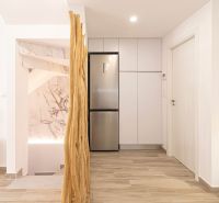 Interior of a holiday apartment with kitchen cabinets, refrigerator, and wooden decor flooring.