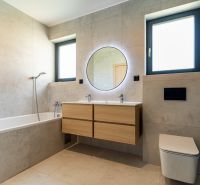 A bathroom in a family house with a bathtub, toilet, mirror, and two windows.