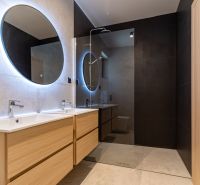 A bathroom in a family house with two sinks and round mirrors with LED lighting.