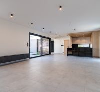 Living room in a family house with a kitchen unit and large glass doors.