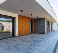 A family house in the Košice area with a terrace, wooden cladding, and paving.
