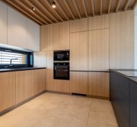 A kitchen in a family house with wooden cabinets and a black countertop.