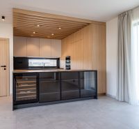 A kitchen with wooden decor, a glass wine cabinet, and a large window in a family house.