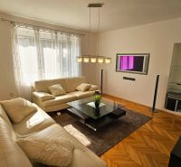 Living room with a white sofa and a wooden decor floor in a 2-room apartment.