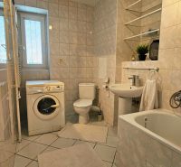 Bathroom of a 2-room apartment with a bathtub, sink, washing machine, and toilet.