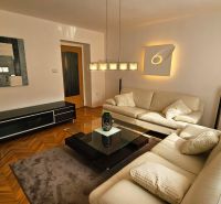 Living room with a leather sofa, glass table, and wood-patterned flooring in a two-room apartment.