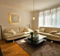 Living room in a 2-room apartment with a white couch and a wooden decor floor.