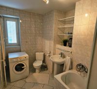 Bathroom with a bathtub, shower, washing machine, and sanitary facilities in a 2-room apartment.